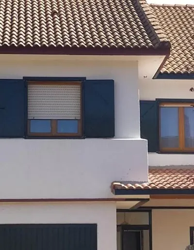 Chalet con ventanas de aluminio y persianas azules