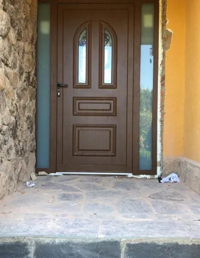 Puerta de entrada de madera con cristales en una fachada de piedra