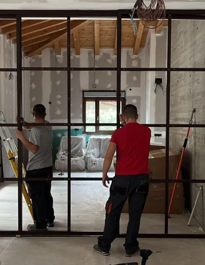 Dos operarios montando una cristalera de perfil fino tipo taller