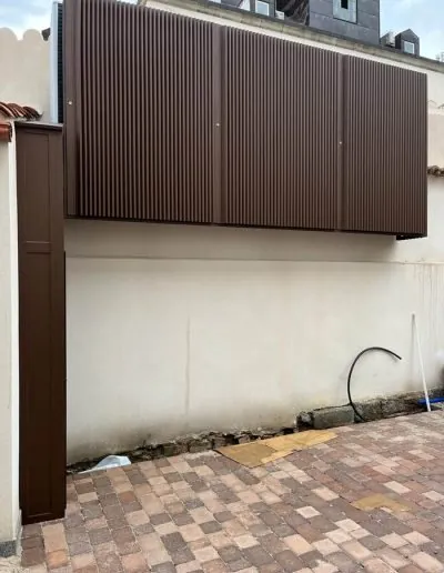 Cerramiento de lamas marrones sobre el muro de un patio