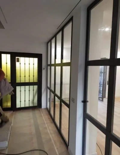 Pasillo separado con una cristalera de perfilería negra