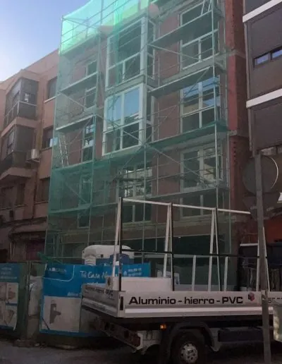 Edificio en obra con andamios y ventanas de aluminio ya colocadas