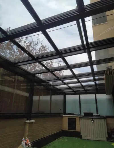 Techo móvil de aluminio y cristal sobre un porche