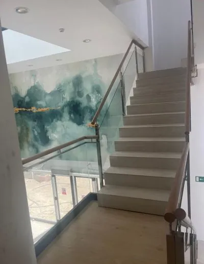Escalera con barandilla de cristal y mural pintado al fondo