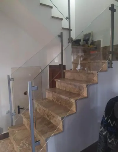 Escalera de madera con barandilla de cristal y pasamanos de acero