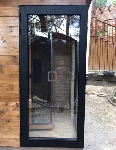 Puerta acristalada de aluminio negro en una pared de madera