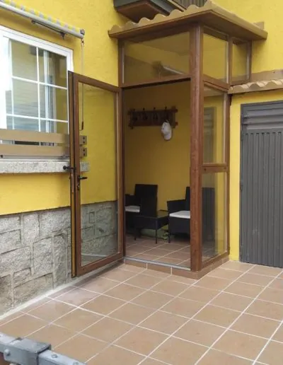Puerta corredera junto al porche de una casa de fachada amarilla