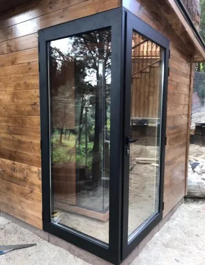 Puerta acristalada de aluminio en una caseta de madera de jardín