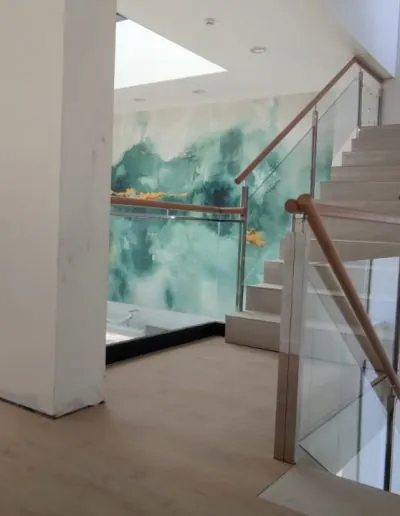 Escalera con barandilla de cristal y mural pintado en la pared