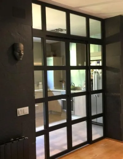 Cristalera de perfilería negra que separa el salón de la cocina