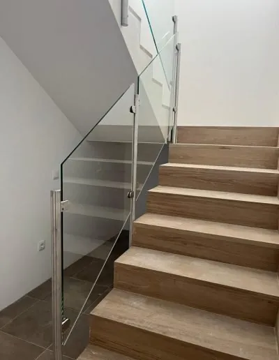 Escalera de madera con barandilla de cristal y pasamanos de acero