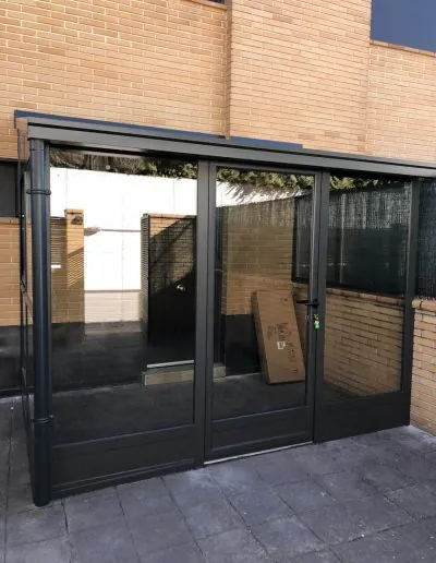 Cerramiento acristalado de perfilería negra con puertas correderas