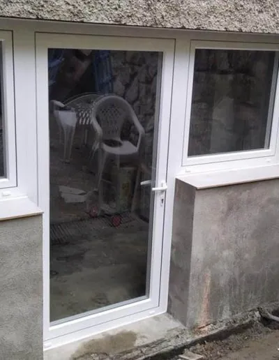 Ventana y puerta de PVC blanco en una fachada de piedra
